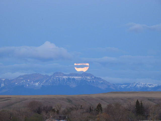 moon obscured by low clouds hovering over the rocky mountains.